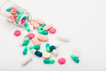 Pills out of a bottle on white background.