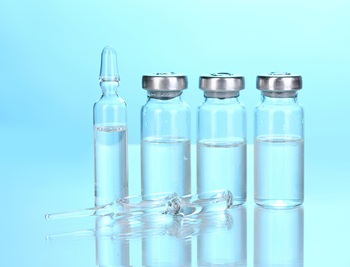 Four ampoules against a blue background showing they are half full of medicine.