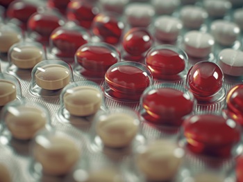 Macro shot of orange and white pills in a blister pack, representing healthcare and pharmaceuticals.