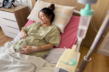 happy pregnant woman patient is resting on a bed in hospital.