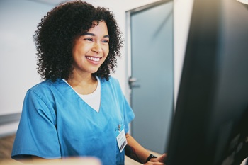 Woman smiling as she enters information into computer.